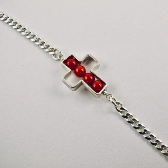 Une chaîne maille gourmette et 4 perles 4 mm de véritable corail rouge de Méditerranée, délicatement enchâssées dans une croix ajourée,  en argent 925/1000e