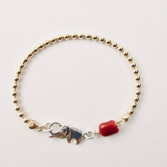Le bracelet Kokkiri, avec son fermoir en forme d'éléphant en argent 925/1000e, est composé d'une chaîne boule en argent plaqué or et d'une grosse perle irrégulière de véritable corail rouge de Méditerranée
