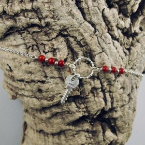 Ce bracelet est composé d'une fine chaîne en argent massif et perles 2,5mm de véritable corail rouge de Méditerranée. Un anneau en argent martelé porte le petit charms. A vous de choisir
