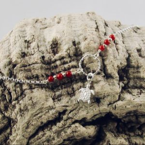 Ce bracelet est composé d'une fine chaîne en argent massif et perles 2,5mm de véritable corail rouge de Méditerranée. Un anneau en argent martelé porte le petit charms. A vous de choisir