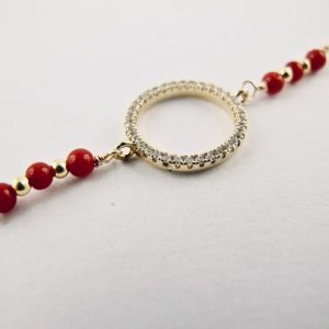 Ce bracelet est composé d'une fine chaîne en argent plaqué or et perles 2,5mm de véritable corail rouge de Méditerranée, reliée à un anneau (ø 13mm) serti de cristaux de swarovski.