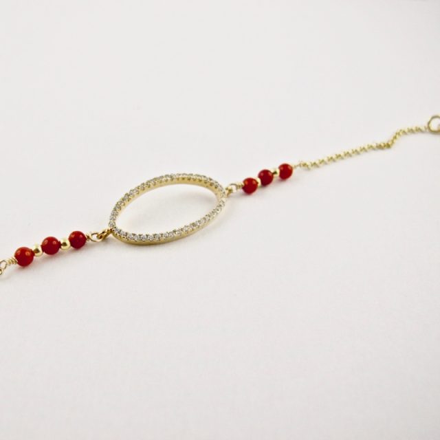 Ce bracelet est composé d'une fine chaîne en argent plaqué or et perles 2,5mm de véritable corail rouge de Méditerranée, reliée à un anneau ovale serti de cristaux de swarovski.