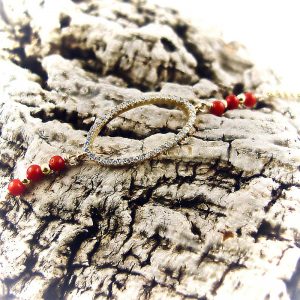 Ce bracelet est composé d'une fine chaîne en argent plaqué or et perles 2,5mm de véritable corail rouge de Méditerranée, reliée à un anneau ovale serti de cristaux de swarovski.