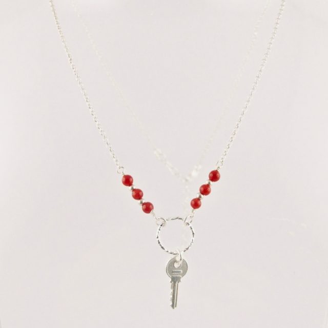 Ce collier est composé d'une fine chaîne en argent massif et perles 2,5mm de véritable corail rouge de Méditerranée. Un anneau en argent martelé porte le petit charms.